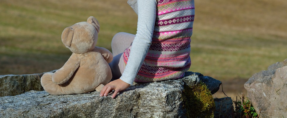 Pige og bamse på sten
