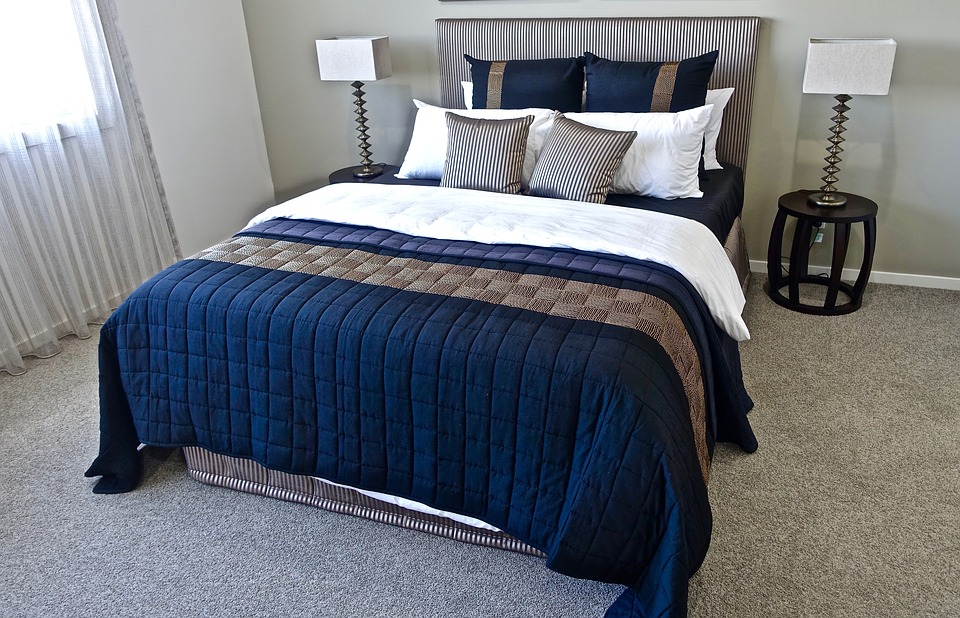 Stilren seng med blåt sengetæppe og puder