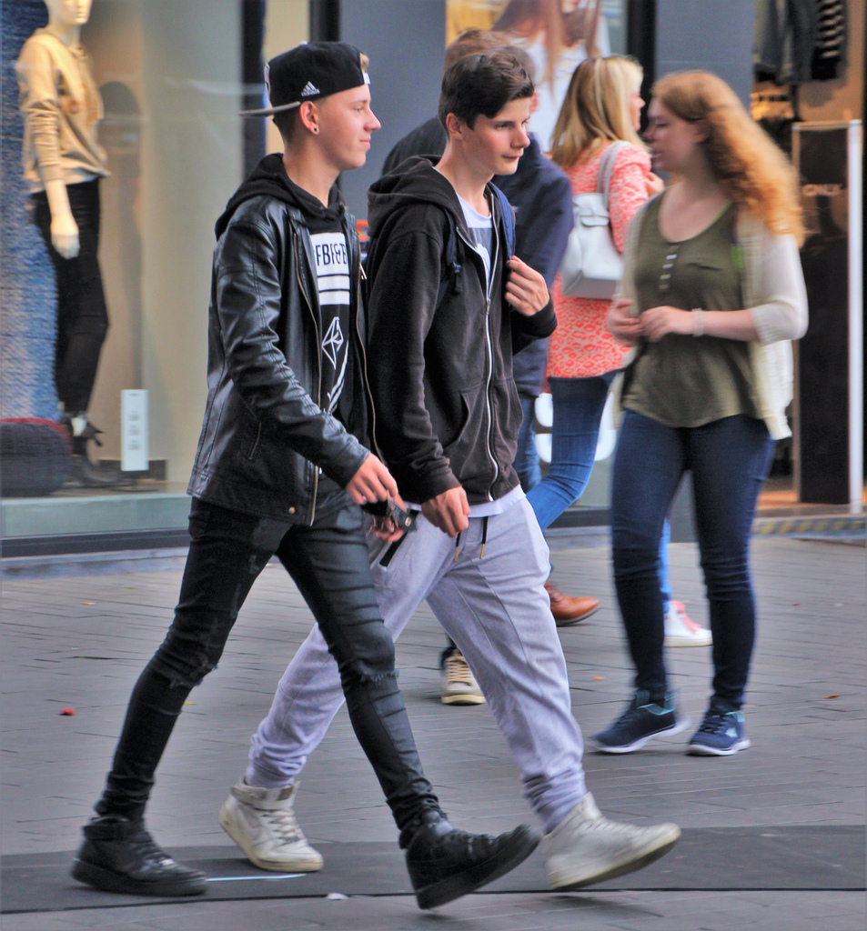2 teenange drenge der går på gaden iført drengetøj