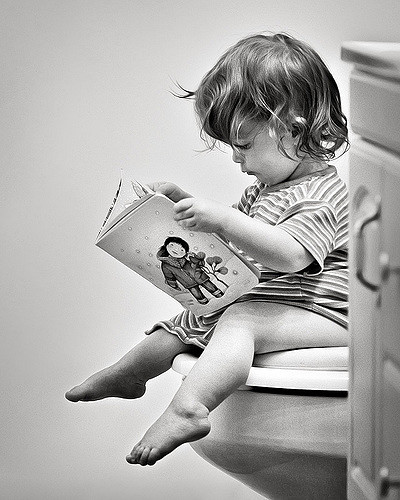Barn sidder på toilet, og læser en bog