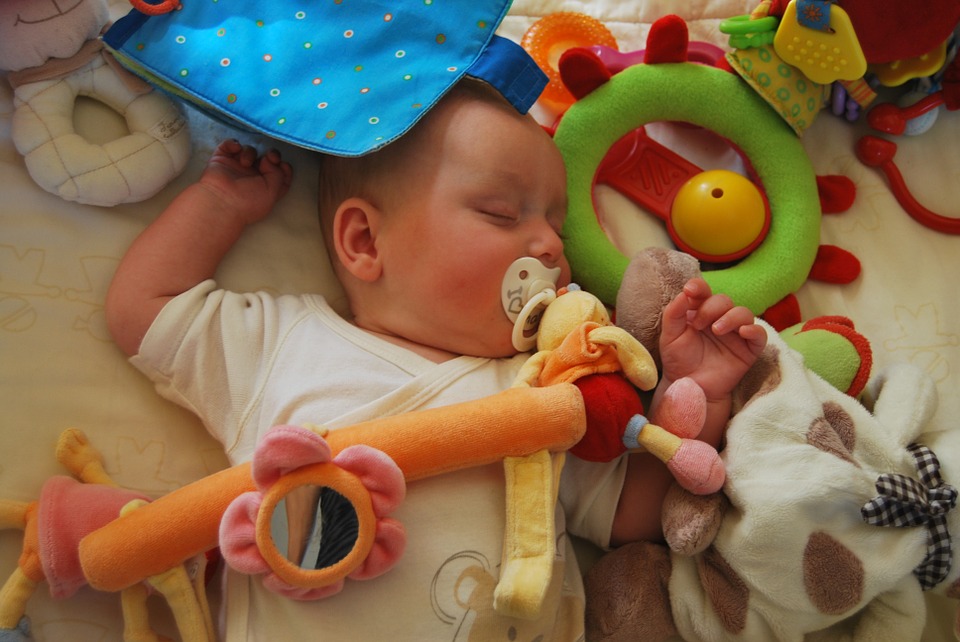 Baby ligger og sover omringet af legetøj