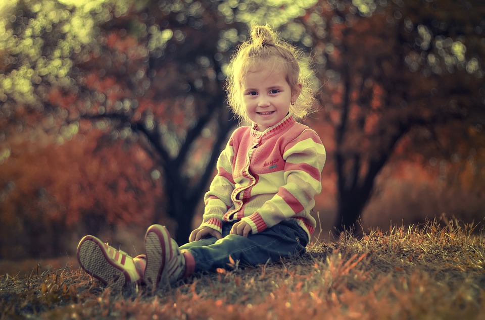 Pige i børnetøj sidder på græsplæne